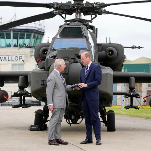 König Charles III. und Prinz William stehen im Army Aviation Centre vor einem "Apache", einem Kampfhubschrauber: Bei ihrem Besuch übergibt der König offiziell das Amt des Oberst des Army Air Corps an William.