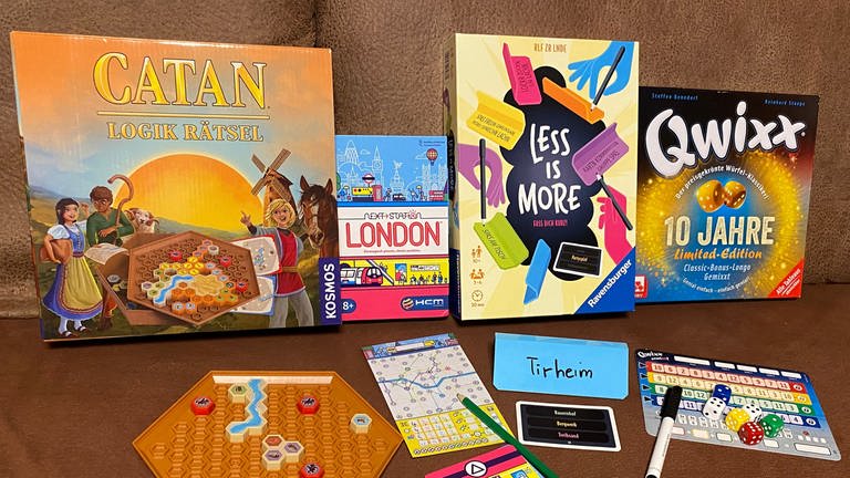 Schachteln der Gesellschaftsspiele "Catan Logik Rätsel", "Next Station London", "Less Is More" und "Qwixx Collection"