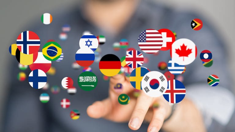 Runde Buttons mit Nationalflaggen schweben in der Luft und werden mit dem Finger angetippt: Insgesamt gibt es auf der Welt ungefähr 7.000 Sprachen. Die Sprachenvielfalt konzentriert sich insbesondere um den Äquator herum.
