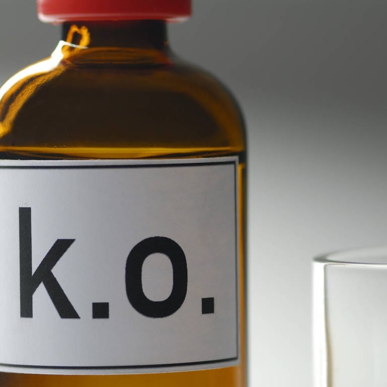 Symbolbild K.o.-Tropfen-Flasche mit danebenstehendem Glas.