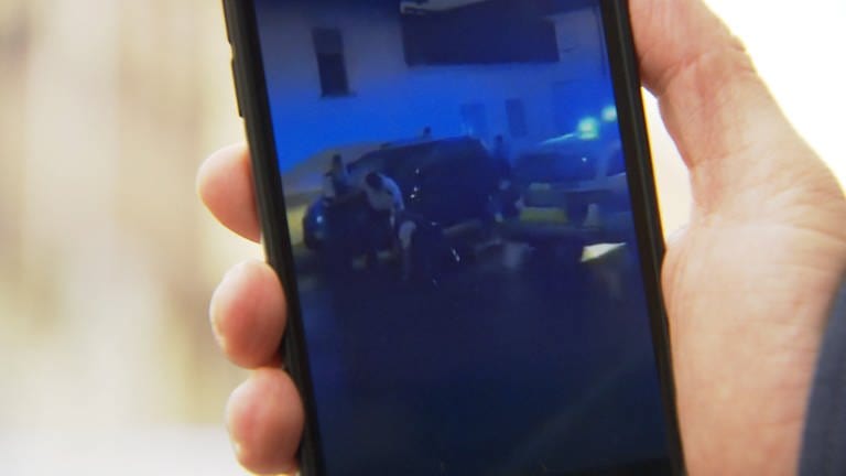 Mögliche Polizeigewalt auf einem Handybildschirm zu sehen