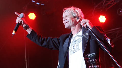 Matthias Reim singt mit erhobenem Arm auf der Bühne