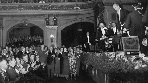Historische Aufnahme: Wilhelm Furtwängler verneigt sich am Dirigentenpult vor Nazi-Granden im Publikum, unter ihnen Adolf Hitler.