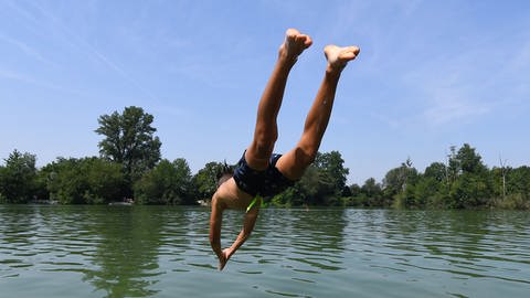 Ein Jugendlicher springt in einen Badesee