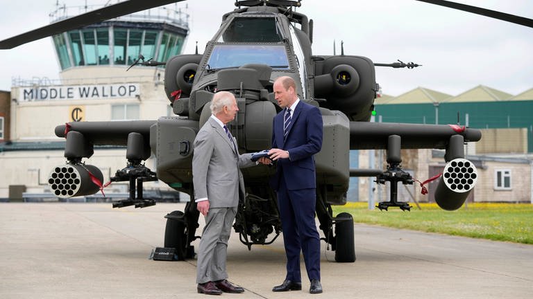 König Charles III. und Prinz William stehen im Army Aviation Centre vor einem "Apache", einem Kampfhubschrauber: Bei ihrem Besuch übergibt der König offiziell das Amt des Oberst des Army Air Corps an William.