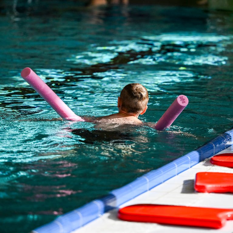 Ein Schüler übt im Rahmen eines Schwimm-Intensivkurses das Schwimmen im Wasserbecken eines Hallenbades mit einer Schwimmnudel (Symbolbild).