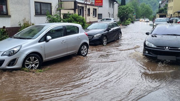 Autos fahren im Stadtteil Altenbach über eine überflutete Straße.
