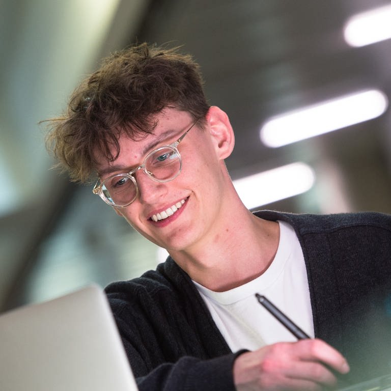 Ein Student mit Brille sitzt am Schreibtisch und schaut in einen Laptop. (Foto: SWR)