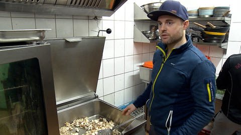 Mann steht in Großküche und kocht gerettete Lebensmittel