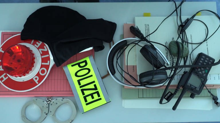 Polizeiausrüstung: Handschelle, Kelle, Funkgerät und Akten liegen auf einem Tisch