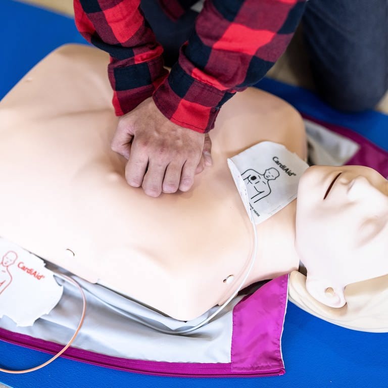 Ein Mensch übt eine Herzdruckmassage an einer Puppe.