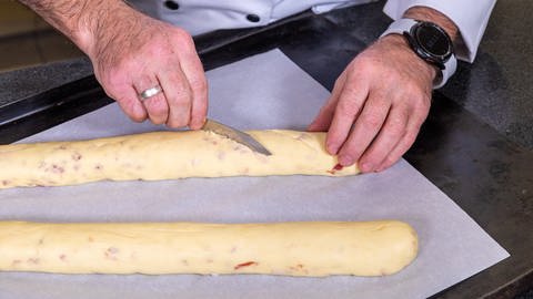 Herzhaftes Baguette mit Speckwürfel backen: Die Baguette auf einer Seite einschneiden.
