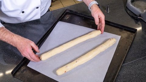 Herzhaftes Baguette mit Speckwürfel backen: Den Teig in zwei längliche Baguettes formen.