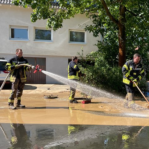 Einsatzkräfte der Feuerwehr spritzen die dicke Schlammschicht von den Straßen in Gemmingen
