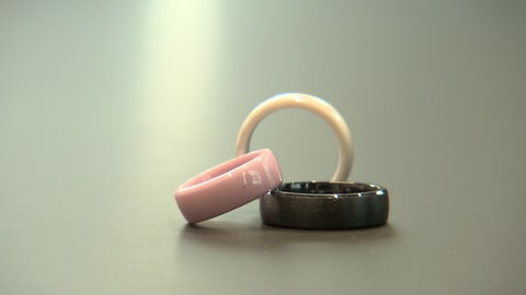 Drei Ringe stehen aneinandergelehnt auf einer Platte - in rosa, braun und beige.