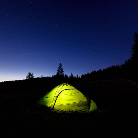 Ein beleuchtetes Zelt bei Nacht im Schwarzwald