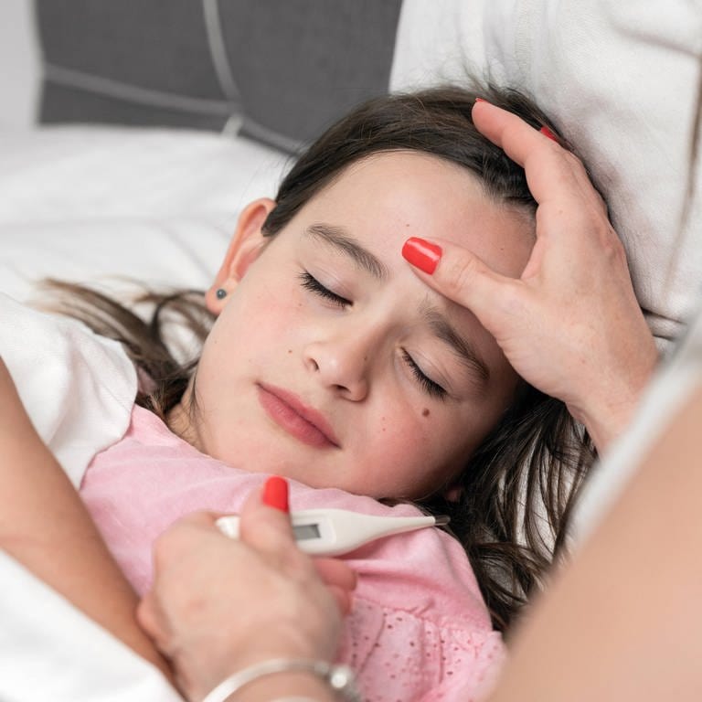 Ein Kind mit Fieber liegt zuhause im Bett