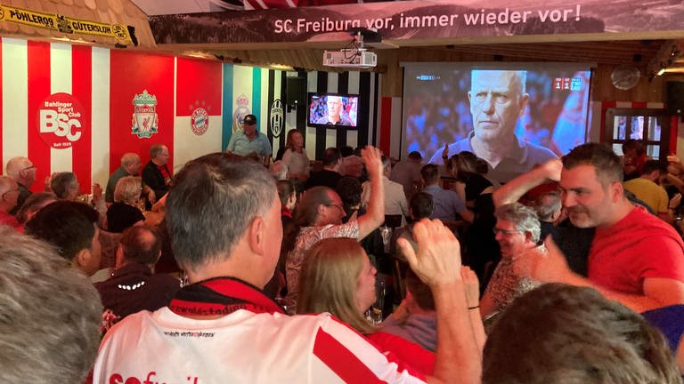 Alle schauen gespannt auf den Bildschirm: SC-Fans schauen in einer Freiburger Kneipe das letzte Spiel von Christian Streich.