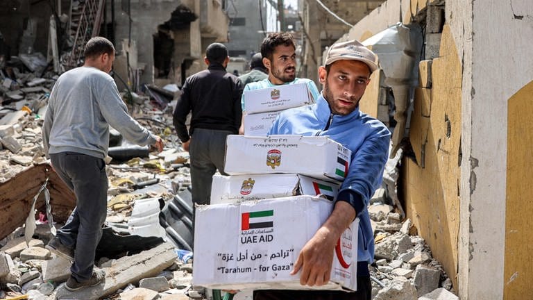 Palästinenser tragen Pakete mit Hilfslieferungen (Foto: AFP)