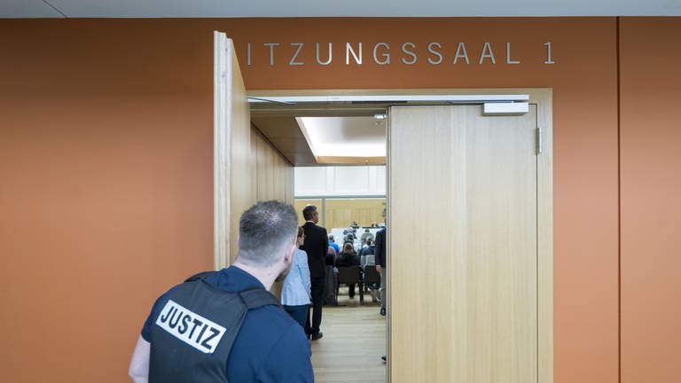 Ein Justiz-Beamter hält die Tür zum Sitzungsaal 1 des Oberlandesgerichts Stuttgart offen. (Foto: EPA)