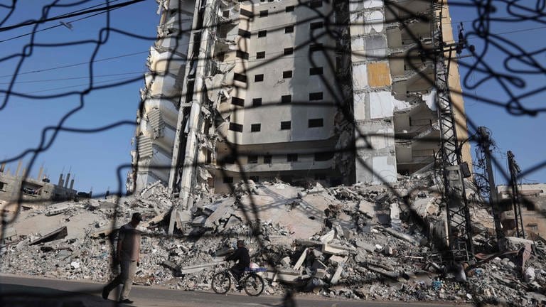 Zwei Männer passieren ein zerstörtes Gebäude in Rafah im Gazastreifen (Foto: AFP)