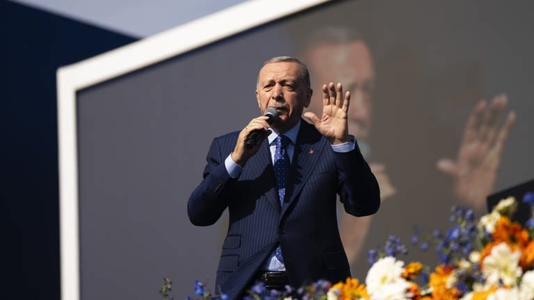 Der türkische Staatspräsident Recep Tayyip Erdogan steht bei einem Wahlkampfauftritt auf einer Bühne und spricht in ein Mikrofon. (Foto: AP)