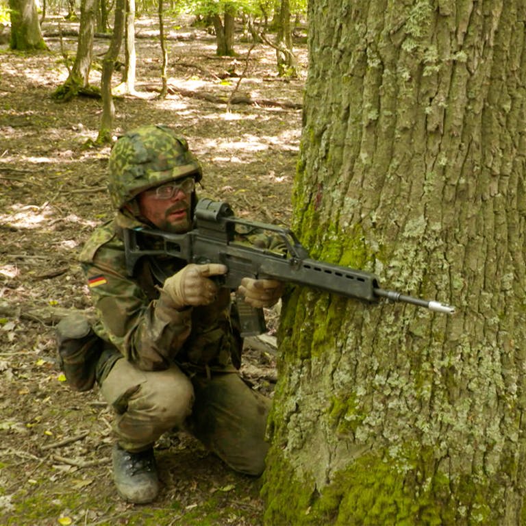 Mann in Tarnkleidung mit Helm und Waffe in Wald. (Foto: SWR)