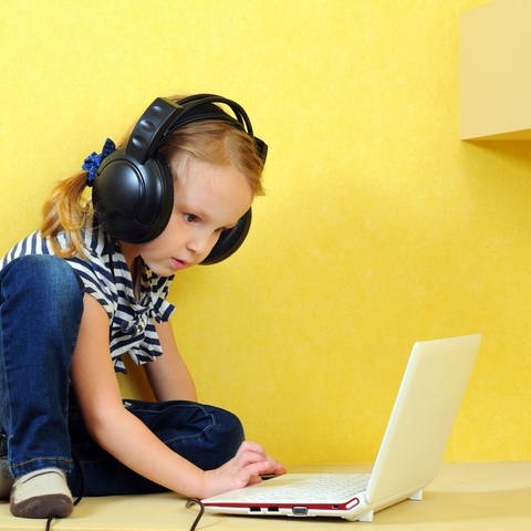 Mädchen sitzt mit Kopfhörern vor einem Laptop. (Foto: Thinkstock)