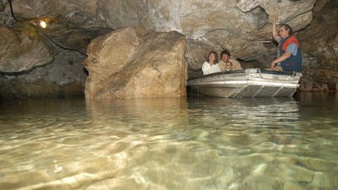 Ein Mann fährt am 16.06.2003 mit seinem Boot eine Familie durch die Wimsener Höhle auf der Schwäbischen Alb.