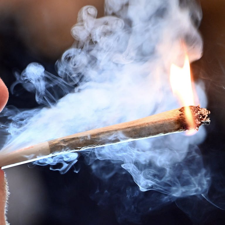 Ein Mann zieht an einem Joint (Foto: IMAGO, Sven Simon)