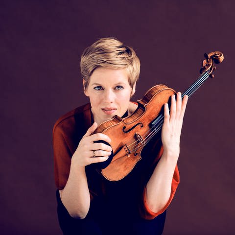 Isabelle Faust (kurzes, blondes Haar) mit Geige vor violletem Hintergrund (Foto: Impresariat Simmenauer, Fotograf: Felix Broede)