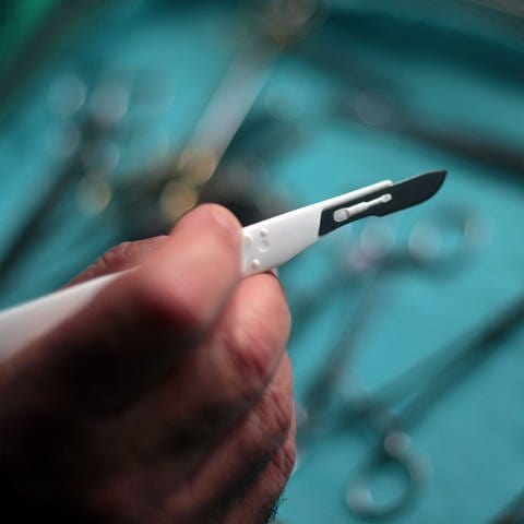 Ein Chirurg hält ein Skalpell in der Hand (Foto: picture-alliance / Reportdienste, picture alliance / dpa | Oliver Berg)