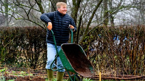 König Willem-Alexander passt bei der Gartenarbeit mit an und kippt Erde aus einer Schubkarre (Foto: IMAGO, IMAGO / PPE)