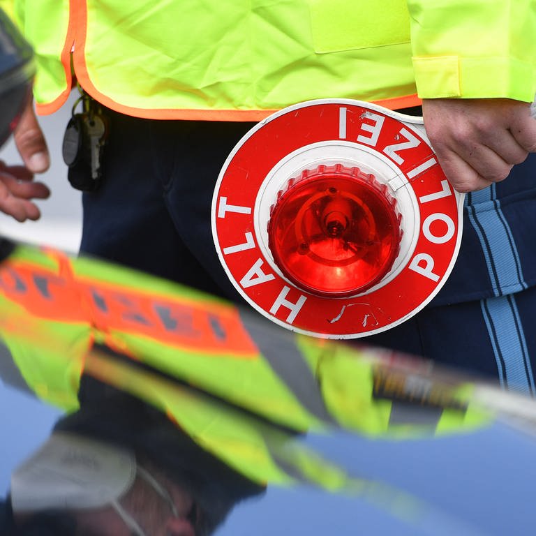 Ein Verkehrspolizist kontrolliert einen Verkehrssünder am Straßenrand (Foto: IMAGO, IMAGO / Sven Simon)