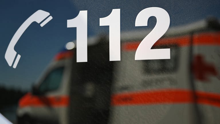 Ein Rettungswagen spiegelt sich in einem Fenster eines anderen Rettungswagen mit der Aufschrift "112".