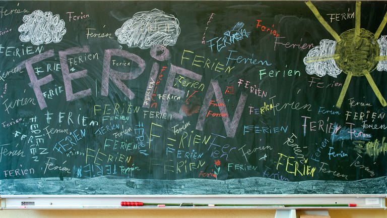 Das Wort "Ferien" steht an einer Tafel in einem Klassenzimmer einer Grundschule. 