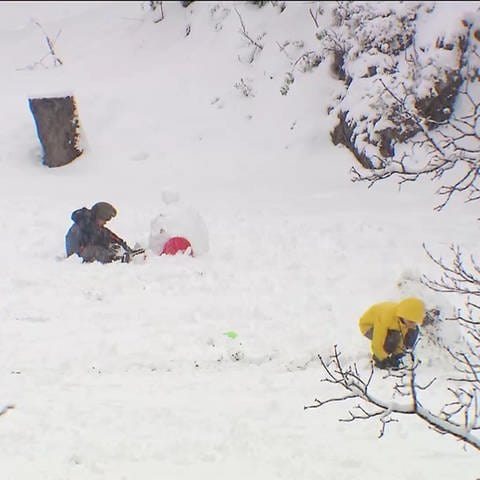 Kinder bauen Schneemänner auf einer vom Schnee bedeckten Wiese