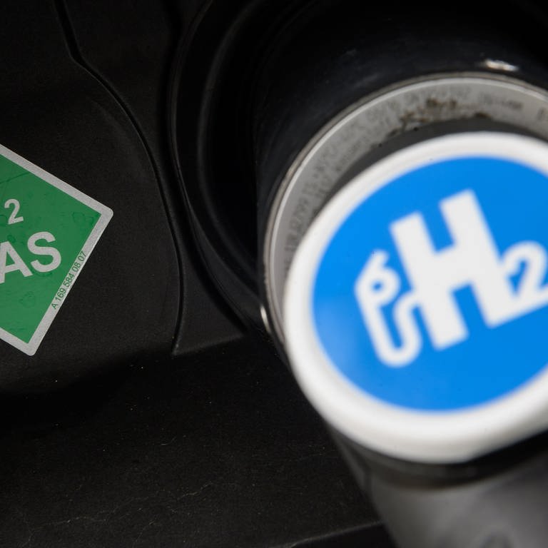 Der Zapfhahn einer Wasserstofftankstelle steckt im Stutzen eines Wasserstoffautos.