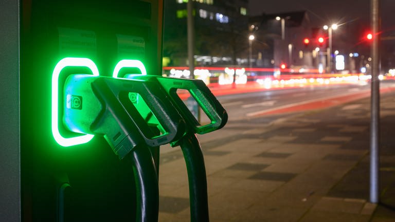 Grün leuchten Ladekabel an einer Schnellladesäule für Elektroautos.