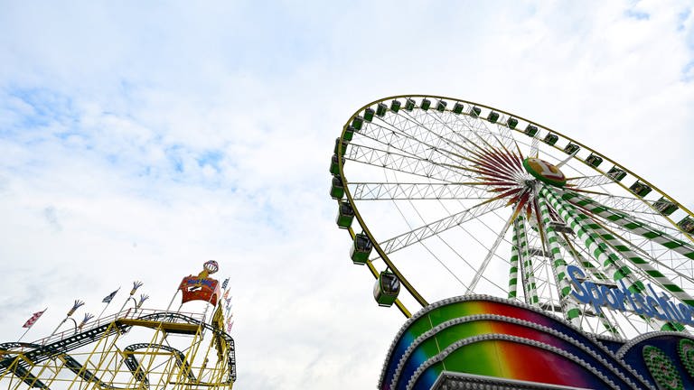 Ein Riesenrad und eine Achterbahn sind auf dem Cannstatter Wasen aufgebaut. Auf dem Stuttgarter Frühlingsfest sind Besucher am Norovirus erkrankt. (Foto: dpa Bildfunk, picture alliance/dpa | Bernd Weißbrod)