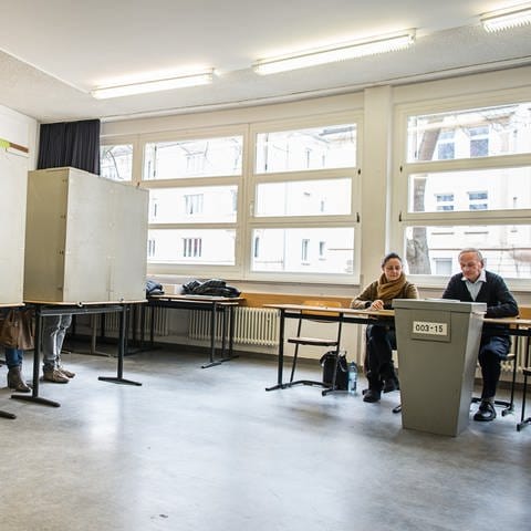 Ein Wahlhelfer und eine Wahlhelferin in einem Wahllokal.