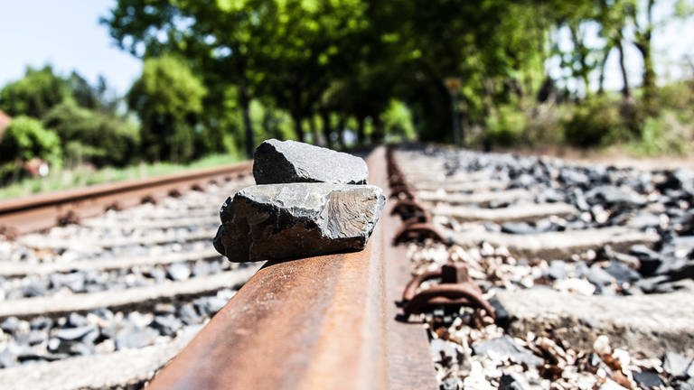 Auf den Gleisen einer Bahnstrecke liegen auf den Schienen Steine (Symbolbild).