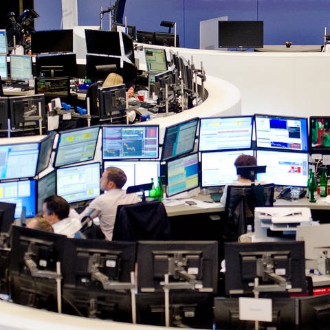 Aktienhändler an der Börse vor Bildschirmen mit den Aktienkursen