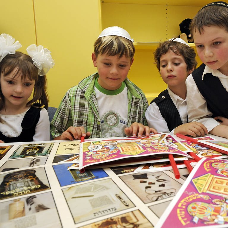 Jüdische Schüler betrachten während der Eröffnung der jüdischen Grundschule in Stuttgart bedruckte Papierbögen.