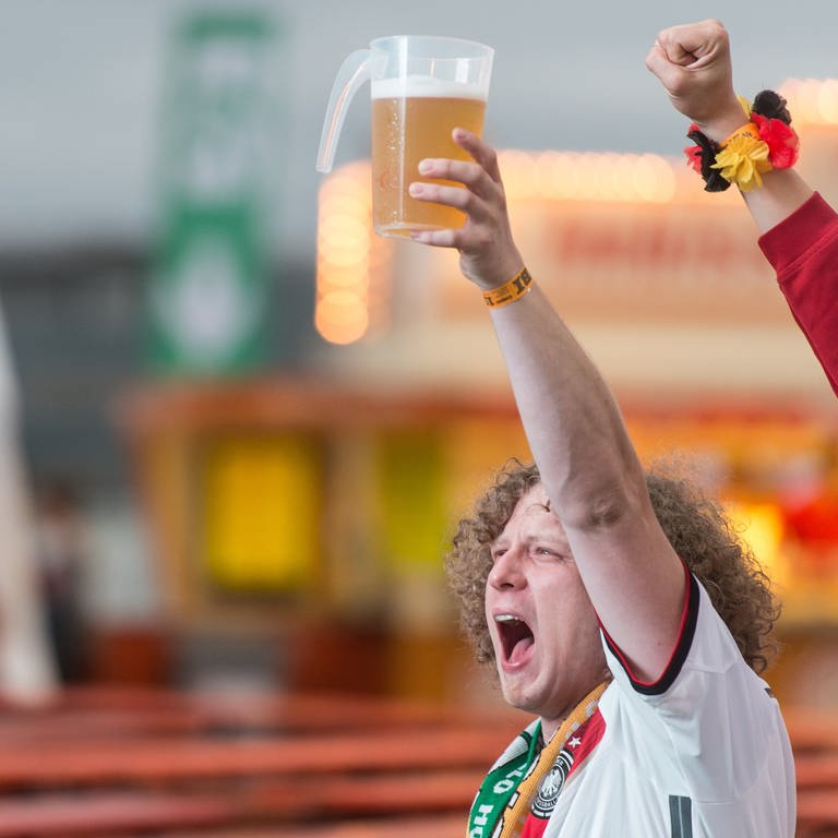 Ein Fan hält während eines EM Spiels ein Bier in der Hand und grölt. 