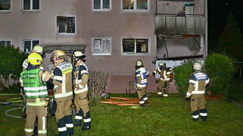 Feuerwehrleute stehen vor einem Mehrfamilienhaus in Stuttgart-Zuffenhausen, in dem am Pfingsmontag ein Brand ausgebrochen war.