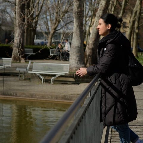 Sina Frehner steht auf einer Brücke auf dem Gelände der Uniklinik Freiburg und schaut nachdenklich in den Teich vor ihr.  (Foto: SWR)