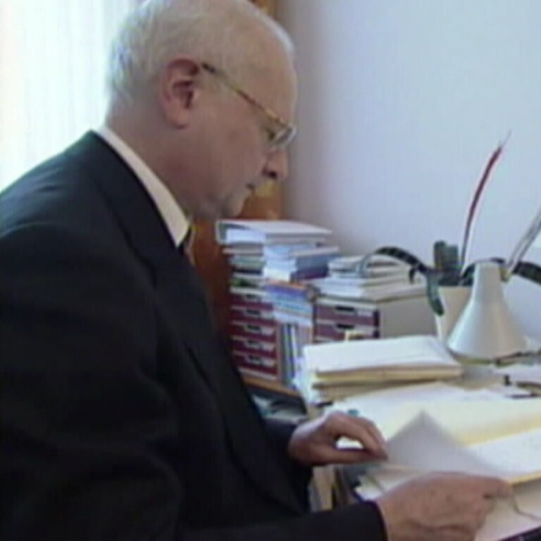 Ex-Erzbischof Robert Zollitsch sitzt an einem Schreibtisch in einem Büro.
