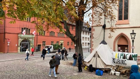 Aktivisten des Freiburger Klimacamps haben mit dem Abbau ihrer Zelte auf dem rathausplatz begonnen. Das Verwaltungsgericht hatte entschieden, dass das Klimacamp für den Weihnachtsmarkt weichen muss.  (Foto: SWR, Jannik Schwab)