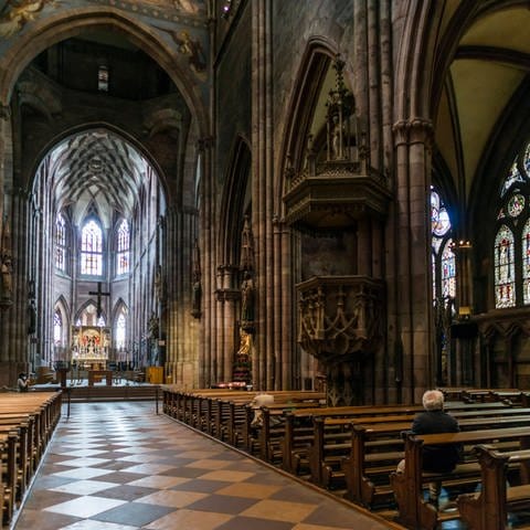 Der Kirchenraum des Freiburger Münsters, ein paar Gläubige sitzen auf den Bänken. (Foto: IMAGO, imagebroker)